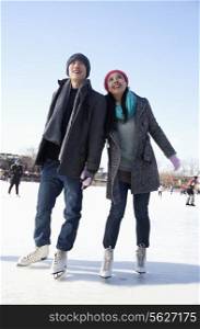 Young couple skating at ice rink