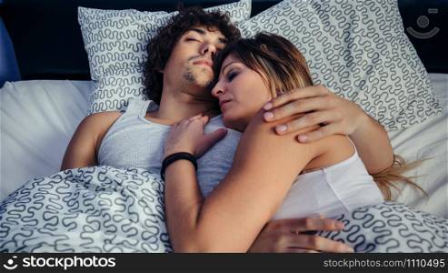 Young couple sleeping embraced in bed at home