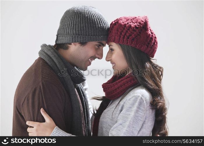 Young couple smiling at each other over grey background