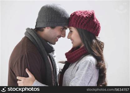 Young couple smiling at each other over grey background