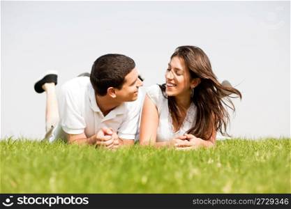 young couple smiling by laying down in a green grass field,outdoor