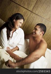 Young couple smiling on the bed and looking at each other
