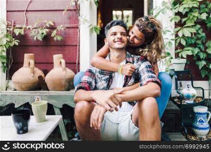 Young couple smiling sitting on the steps outside the wooden cabin