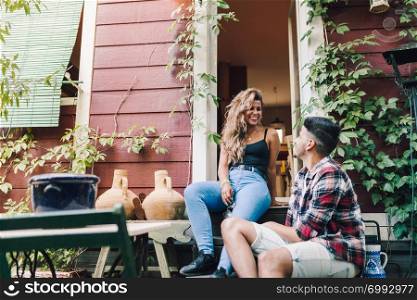 Young couple smiling sitting on the steps outside the wooden cabin