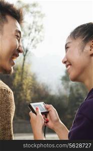Young couple smiling, woman holding digital camera