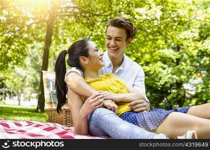 Young couple snuggling together on picnic blanket