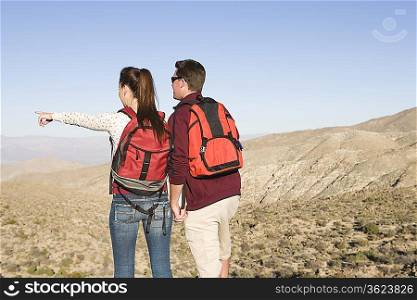 Young couple stand looking at view woman points