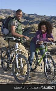 Young couple stand smiling with mountain bikes