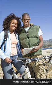 Young couple stand with map and mountain bikes