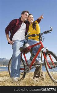 Young couple stand with mountain bike man pointing