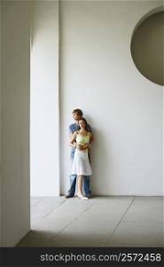 Young couple standing against a wall
