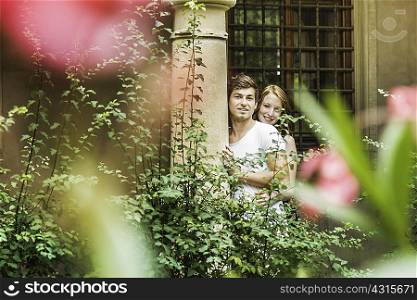 Young couple standing against pillar in garden