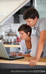 Young couple standing in kitchen with laptop