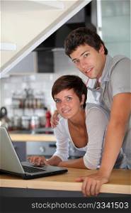 Young couple standing in kitchen with laptop