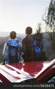 Young couple standing next to the car and looking at the mountains