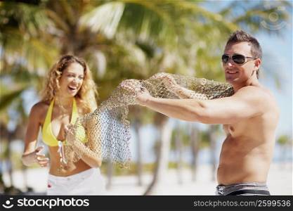 Young couple standing on the beach and holding a fishing net