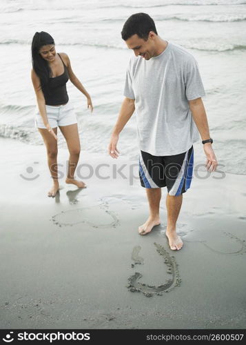 Young couple standing on the beach and looking down