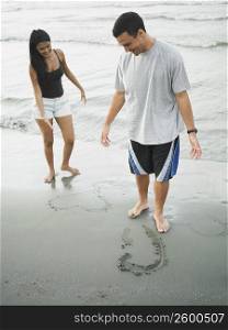 Young couple standing on the beach and looking down