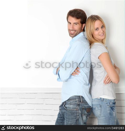 Young couple standing on white wall