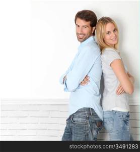 Young couple standing on white wall