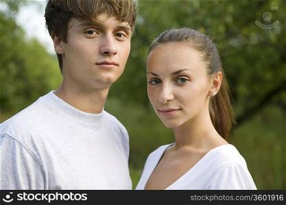 Young couple standing side to side in orchard