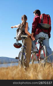 Young Couple standing with mountain bikes holding hands back view.