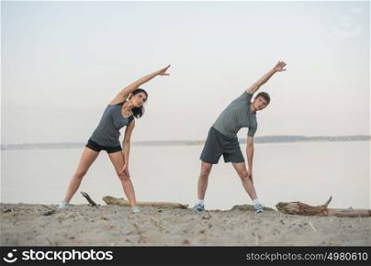 Young couple stretching on beach