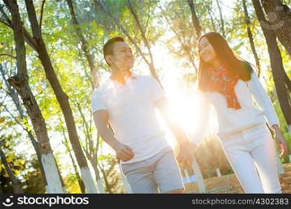 Young couple strolling in sunlit autumn park, Beijing, China