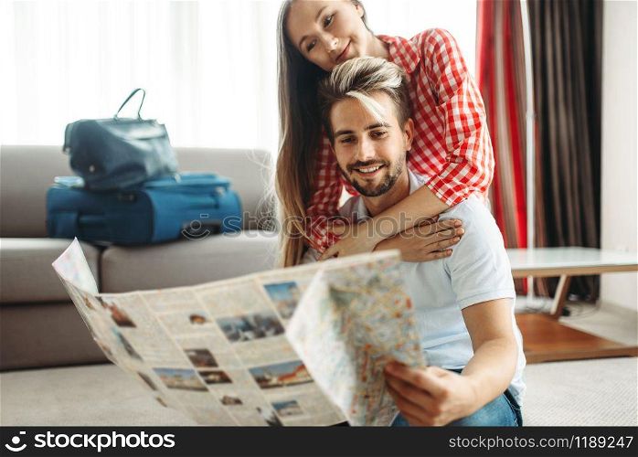 Young couple studying a map before summer journey. Fees on vacation concept. Preparation for summer holidays. Young couple studying a map before summer journey