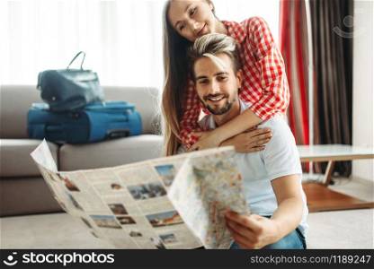 Young couple studying a map before summer journey. Fees on vacation concept. Preparation for summer holidays. Young couple studying a map before summer journey