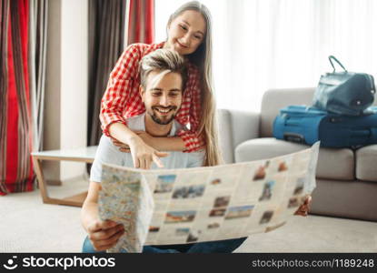 Young couple studying a map before summer journey. Fees on vacation concept. Preparation for summer holidays. Young couple studying a map before summer journey