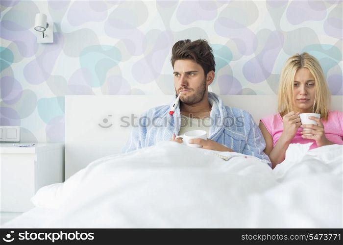 Young couple suffering from cold while relaxing in bed at home
