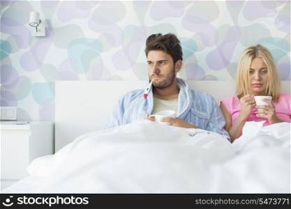 Young couple suffering from cold while relaxing in bed at home