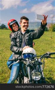 Young couple taking a selfie on the motorcycle outdoors. Couple taking a selfie on the motorcycle