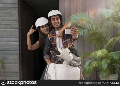 Young couple taking selfie sitting on motorbike