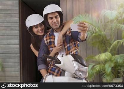 Young couple taking selfie sitting on motorbike