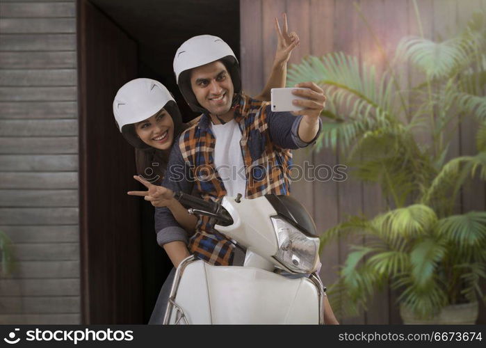 Young couple taking selfie sitting on motorbike