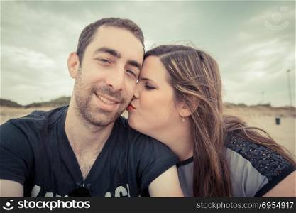 Young couple taking selfie with smartphone or camera at the beach.