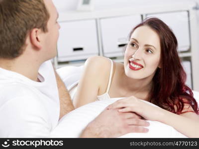 Young couple talking while lying in bed in the morning. Woke up together