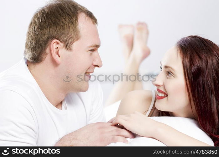 Young couple talking while lying in bed in the morning. Woke up together