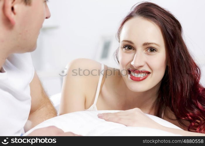 Young couple talking while lying in bed in the morning. Woke up together