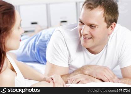 Young couple talking while lying in bed in the morning. Woke up together