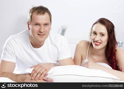 Young couple talking while lying in bed in the morning. Woke up together