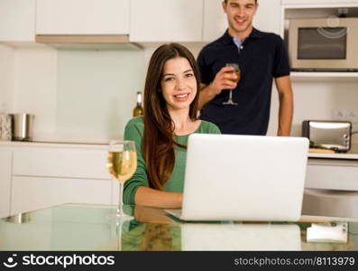 Young couple tasting wine and the women working on a laptop