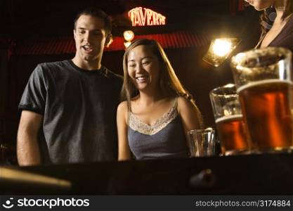 Young couple teamed up at foosball game in pub.