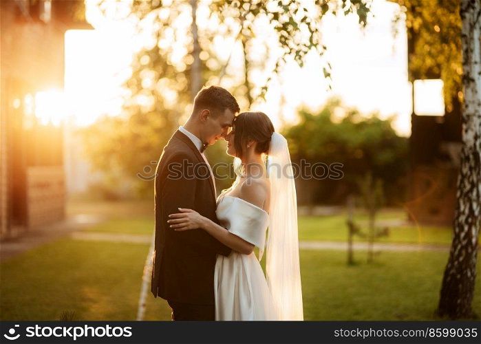young couple the groom in a black suit and the bride in a white short dress on a walk in the village