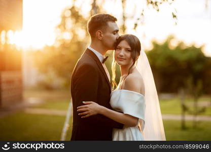 young couple the groom in a black suit and the bride in a white short dress on a walk in the village