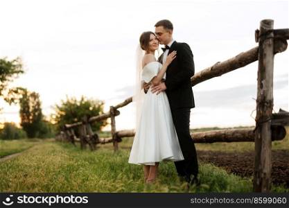 young couple the groom in a black suit and the bride in a white short dress on a walk in the village