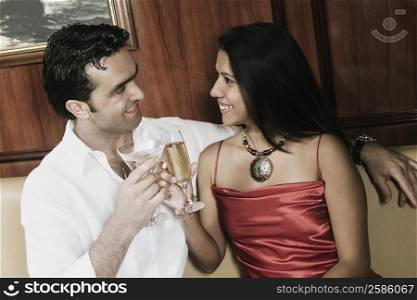 Young couple toasting with champagne flutes and smiling