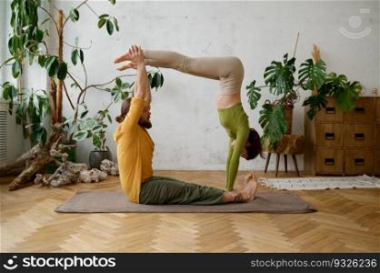 Young couple training yoga in pair doing acrobatic plank together. Millennial man and woman making balancing exercise. Young couple training yoga in pair doing acrobatic plank together
